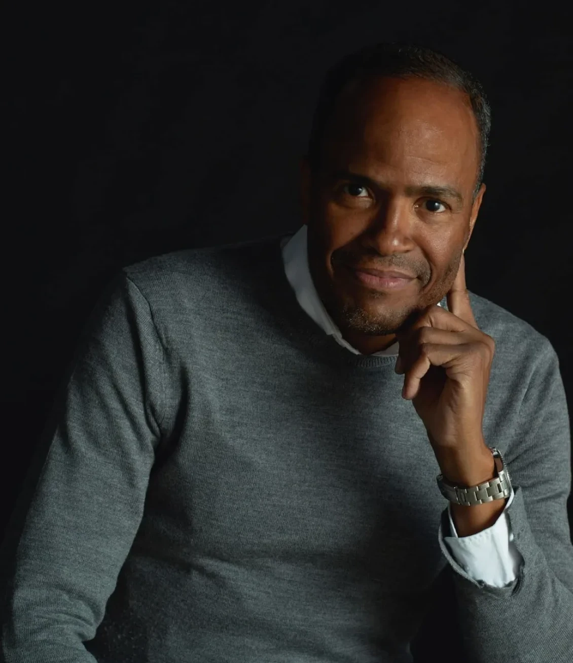 Man in gray sweater with thoughtful expression.