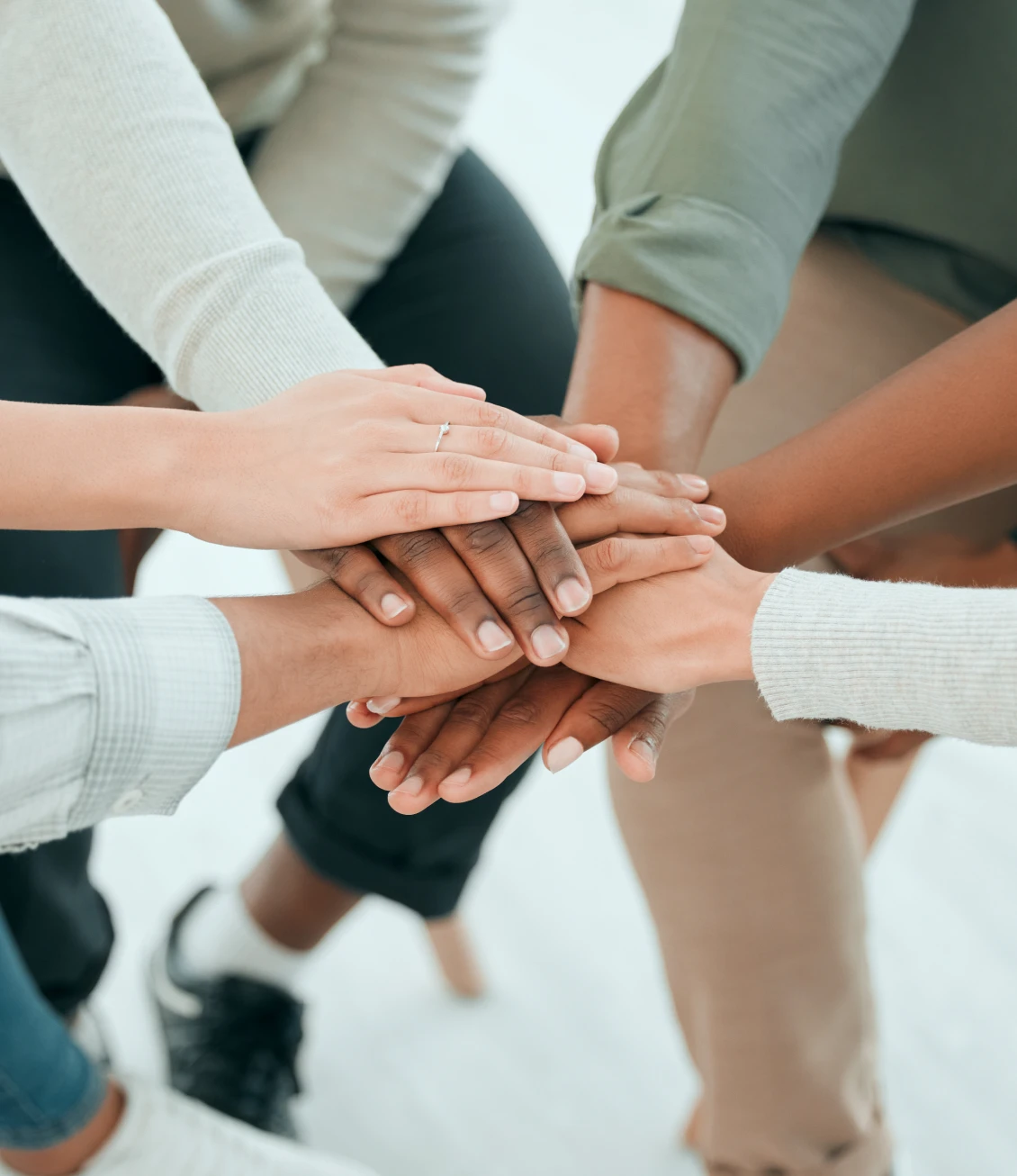 Diverse hands stacked in teamwork gesture.